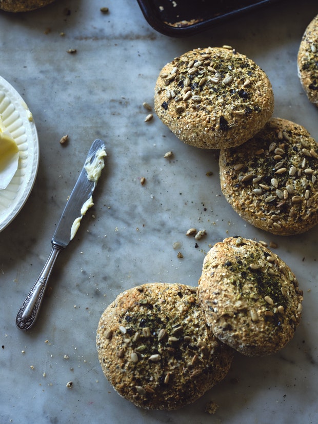 Small round homemade breads topped with seeds on a marble counter