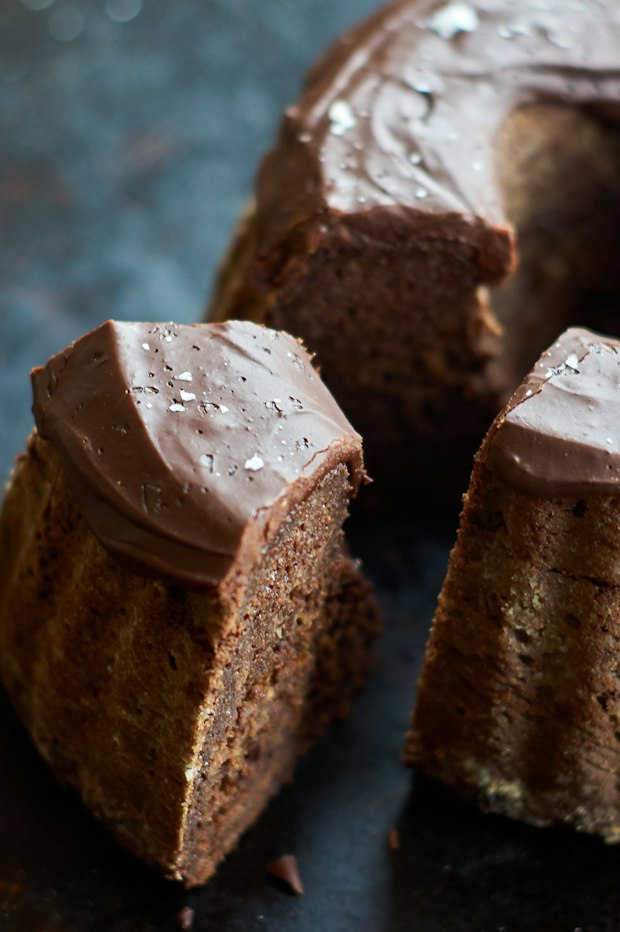 a close up photo of a slice of chocolate bundt cake with thick chocolate frosting on the top