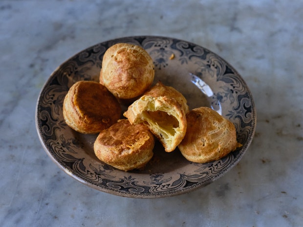 Gougeres on a plate one with a bite taken out of it