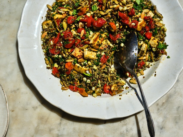 plate of quinoa mixed with roasted tomatoes, tofu, seeds, and kale