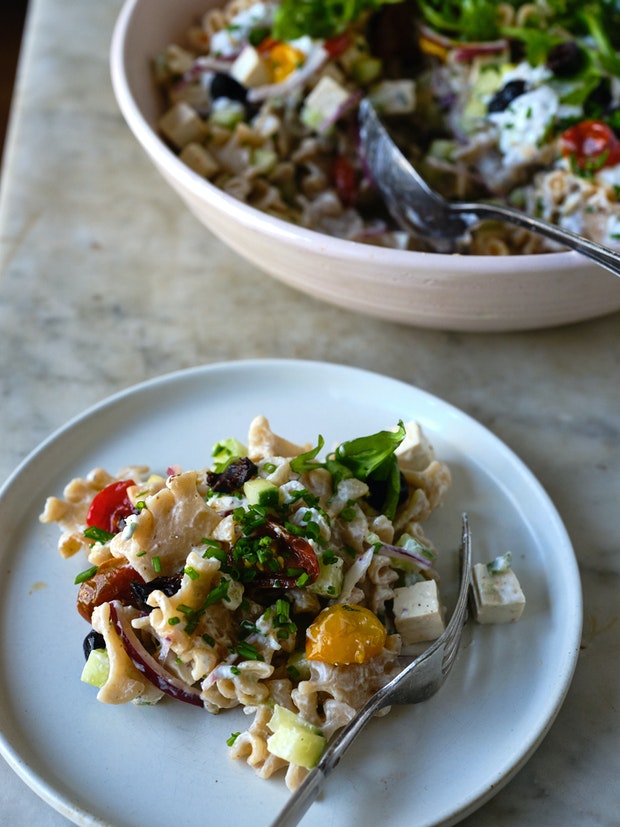 an individual plate of pasta salad including with a fork