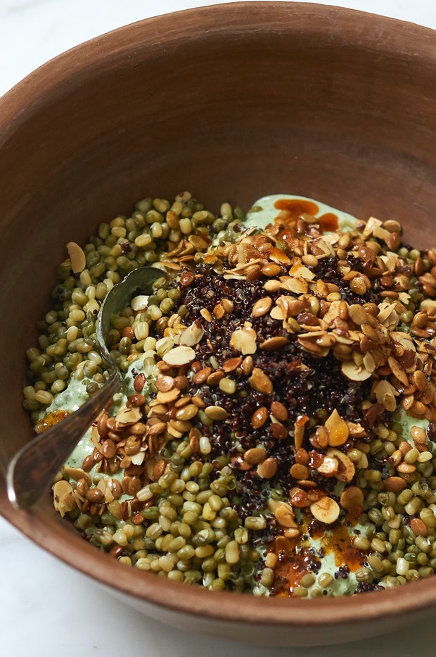 Big bowl filled with mung beans, quinoa, yogurt dressing and paprika oil