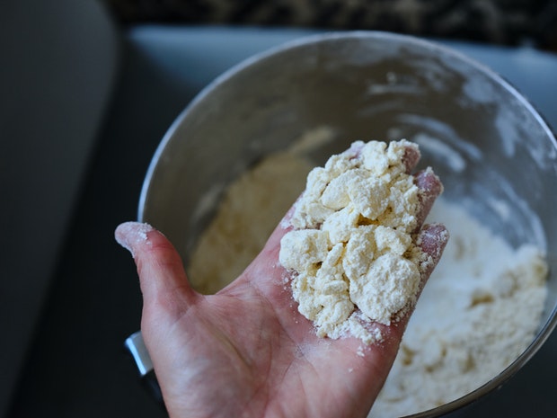 shards of butter coated in flour in baker's hand