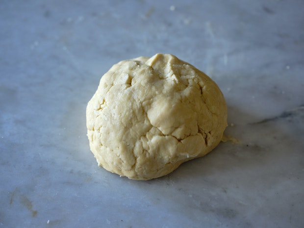 pie dough shaped into a ball on marble counter