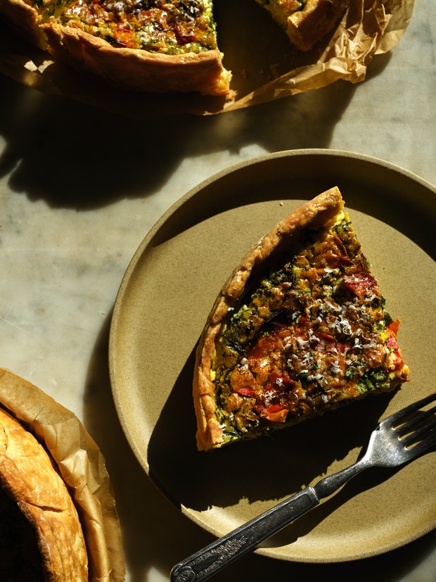 a wedge of quiche with spinach and roasted tomatoes