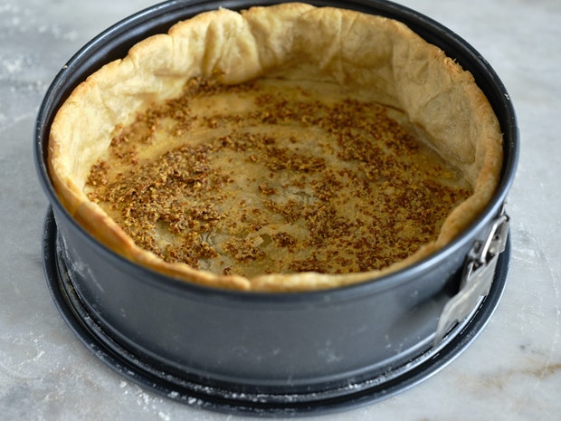 preparing a quiche crust with a thin layer of mustard before filling and baking