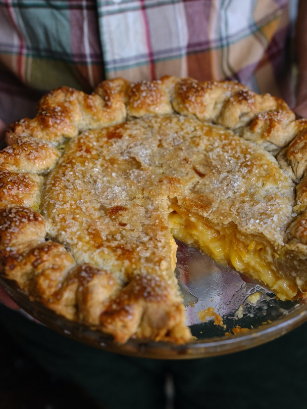 partial lemon pie being held at waist level by man