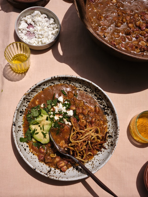 A bowl of Vegan Pozole topped with Homemade Tortilla Strips, Avocado, Cabbage and Toasted Pepitas